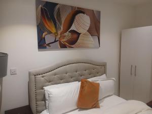 ein Schlafzimmer mit einem Bett und einem Gemälde an der Wand in der Unterkunft Embassy Gardens- Frank Homes in Accra + 43 Fotos