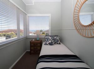新普利茅斯Blue Water Cottage - with beachfront coastal views的一间卧室配有一张带镜子的床和窗户