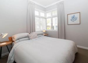 新普利茅斯Blue Water Cottage - with beachfront coastal views的一间带床和窗户的白色卧室 更多13张照片