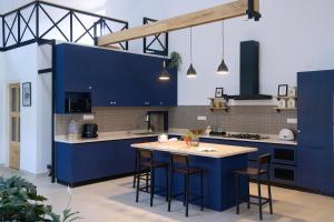 a kitchen with blue cabinets and a island with stools at Okka by Raho - A colonial style villa in Coorg in Siddapur