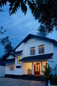 a white house with its lights on at Okka by Raho - A colonial style villa in Coorg in Siddapur