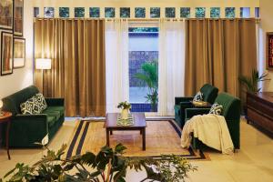 a living room with two green couches and a table at Okka by Raho - A colonial style villa in Coorg in Siddapur