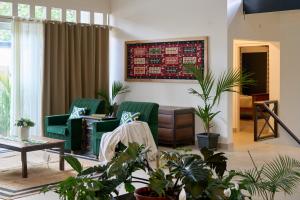a living room with green chairs and plants at Okka by Raho - A colonial style villa in Coorg in Siddapur