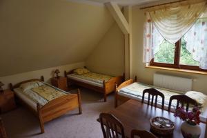 Pokój z 3 łóżkami, stołem i oknem w obiekcie Ośrodek Wypoczynkowy Sowa w mieście Lipniak