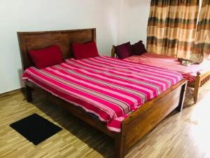 a large wooden bed in a room with red pillows at Chapa Resting Place in Dickwella