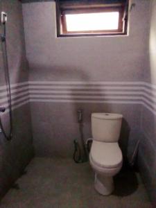 a bathroom with a white toilet and a window at Chapa Resting Place in Dickwella