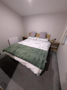 ein Schlafzimmer mit einem großen Bett und einer grünen Decke in der Unterkunft Seascape Caravan in Kinmel Bay + 21 Fotos