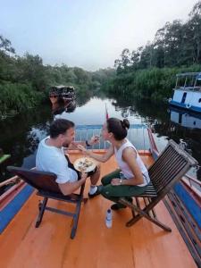a man and woman eating food on a boat on a river at Orangutan Borneo Tour Tanjung Puting in Pangkalan Bun +36 photos