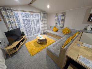 ein Wohnzimmer mit Sofa und Fernseher in der Unterkunft Seascape Caravan in Kinmel Bay