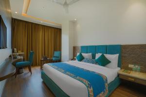 アムリトサルにあるHotel SG Continental Amritsar !! Prime Location ! Parking ! Open terraceのベッドルーム1室(大型ベッド1台、青いヘッドボード付)