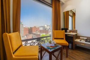 アムリトサルにあるHotel SG Continental Amritsar !! Prime Location ! Parking ! Open terraceのデスク、椅子2脚、大きな窓が備わる客室です。
