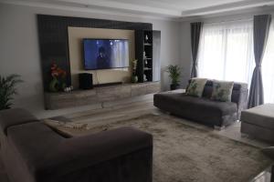 a living room with a couch and a flat screen tv at GuestHouseVine&Stone in Clarens