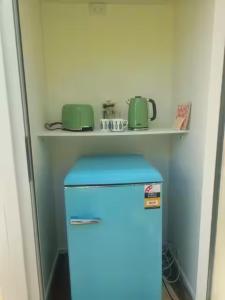 Ein blauer Kühlschrank mit zwei grünen Tassen auf einem Regal. in der Unterkunft Glamping with stunning sea view in Nelson