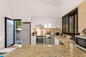 a kitchen with white cabinets and granite counter tops at Zeus Holiday Home in Pissouri
