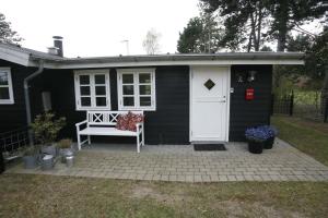 a black shed with a white door and a bench at Child-Friendly Holiday 500 Meters From The Beach in Nykøbing Sjælland