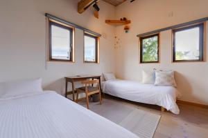 a room with two beds and a desk and windows at Villa Katarima 西軽井沢 in Miyota