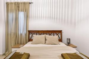 a bedroom with a bed with white sheets and a window at Zeus Holiday Home in Pissouri