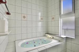 a bath tub in a white tiled bathroom at 海徒歩1分アメリカンビレッジまで7分周辺には飲食店多数の北谷エリアSunabeNest in Chatan +34 photos