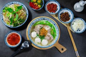 a table with bowls of soup and bowls of food at Tamcoc De Master Lux Bungalow in Ninh Binh