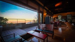 a balcony with chairs and tables and a view of the ocean at Kaze no Tani no Iori in Gamagori