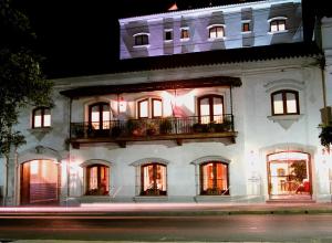 a white building with windows and a balcony at night at Solar De La Plaza in Salta