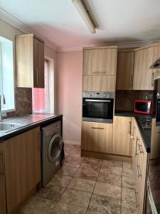 eine Küche mit Holzschränken, einer Waschmaschine und einem Trockner in der Unterkunft Peaceful Family Home in Tilbury with Garden Parking for 3 Cars in Low Street
