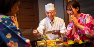 a man and two women sitting at a table with food at Kaze no Tani no Iori in Gamagori