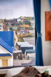 a view of a city from a window with a blue roof at Beyoung Hotel Dalat in Da Thanh +53 photos