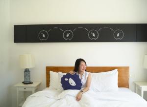een vrouw in bed met een kussen bij Kokotel Khao Lak Isara Casa in Khao Lak