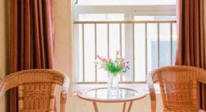 een tafel met een vaas vol bloemen naast een raam bij Shell Zaozhuang Taierzhuang Ancient City East Gate Hotel in Yanzibu