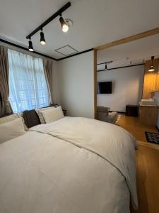 a bedroom with a large white bed in front of a window at The Bunkhouse Hakuba by Mr T in Hakuba