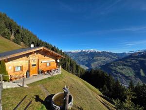 Una cabaña de troncos en una colina con una persona de pie frente a ella. en Chalet Nase at 1700m in the Zillertal, en Grün