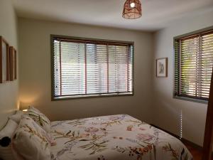 a bedroom with a bed and two windows at Ferntree Hollow - private, peaceful, walk to town in Maleny
