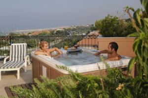 皮耶特拉桑塔的住宿－阿瑞安娜酒店，坐在阳台上热水浴缸中的男女