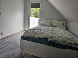 a bed in a white room with a window at Leśny Zakątek Świączyń 