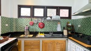 een keuken met groene betegelde muren en een wastafel bij Per La Villa Khao Lak in Khao Lak