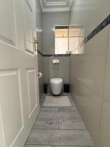 a white bathroom with a toilet and a window at The Ocean Nook - Modern Beach Condo in Gqeberha +7 photos