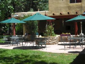 een groep tafels en stoelen met blauwe parasols bij El Pueblo Lodge in Taos