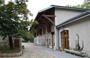 a white building with a wooden roof and a sidewalk at La Ferme du Lignon in Geneva