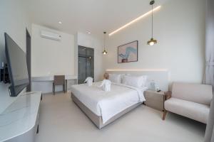 ein weißes Schlafzimmer mit einem Bett und einem Stuhl in der Unterkunft HappyHouse in Pattaya South