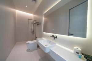 ein weißes Badezimmer mit Waschbecken und Spiegel in der Unterkunft HappyHouse in Pattaya South
