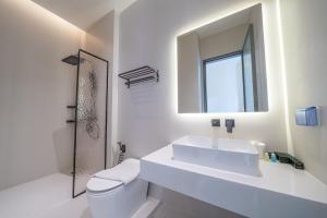 ein weißes Badezimmer mit Waschbecken und Spiegel in der Unterkunft HappyHouse in Pattaya South