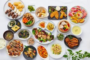 a table with many plates of food on it at Sotetsu Fresa Inn Yodoyabashi in Osaka