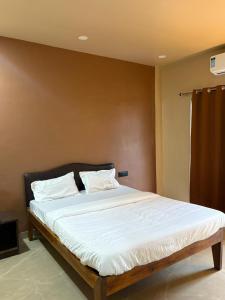 Un dormitorio con una cama grande con sábanas blancas. en Art of greens, en Mahabaleshwar