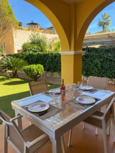 een witte tafel met stoelen en een fles wijn bij Beautiful apartment with gardens - sea and mountain views in Isla Plana