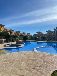 een groot zwembad in een tuin met huizen bij Beautiful apartment with gardens - sea and mountain views in Isla Plana