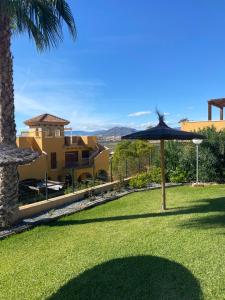 een gazon met een parasol voor een gebouw bij Beautiful apartment with gardens - sea and mountain views in Isla Plana