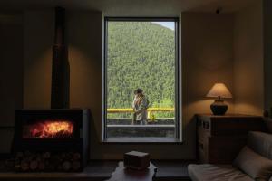 a person standing outside a large window in a room at Shan shang shan HOTEL in Mount Siguniang