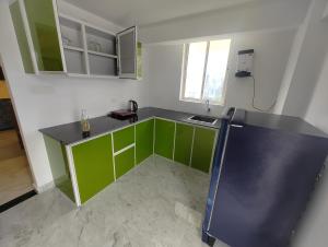 a kitchen with green cabinets and a black counter top at Rajdhani Hospitality in Kazhakuttam