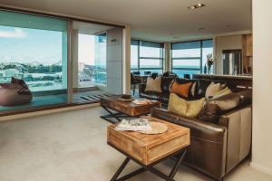 a living room with leather furniture and large windows at Liardett Penthouse - Inner city accommodation in New Plymouth